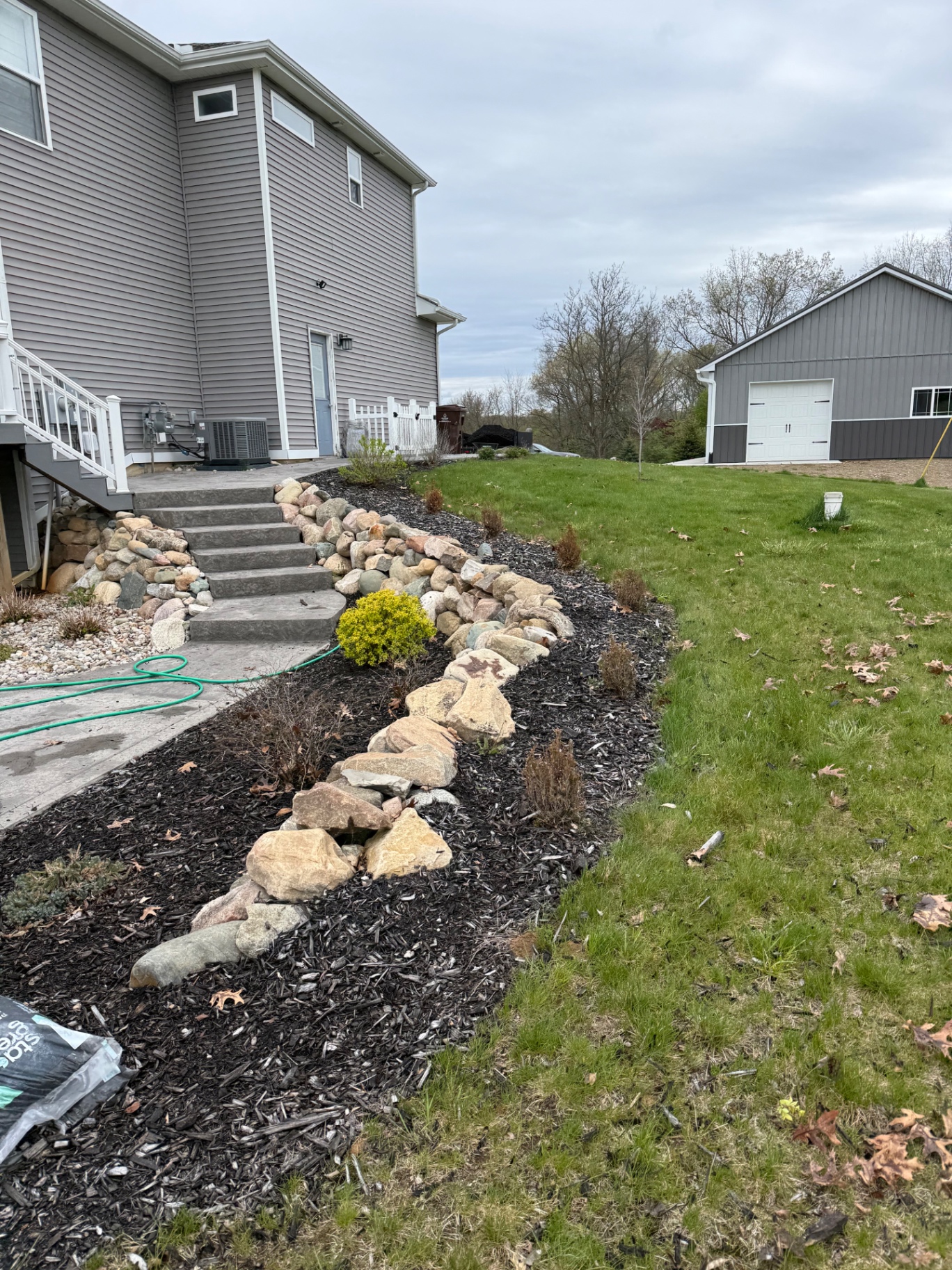 Natural fieldstone border curving along a mulch bed beside concrete steps